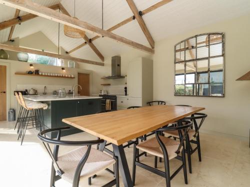 a kitchen and dining room with a wooden table and chairs at Hawthorn Barn in Northleach