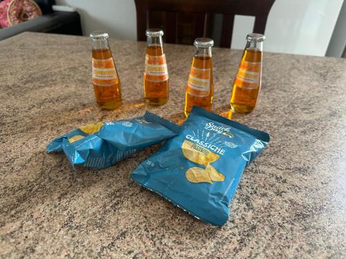 three bottles of beer and a bag of crackers on a table at Mya’s Home in Cinisello Balsamo