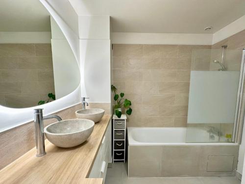 une salle de bain avec deux lavabos, une baignoire et un miroir dans l'établissement Charming House 15 minutes from Paris, à Houilles
