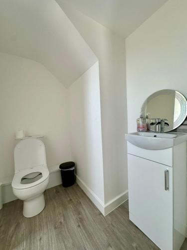 a white bathroom with a toilet and a sink at Wellingborough Guest House in Wellingborough