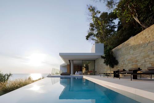 a house with a swimming pool next to the ocean at Opsis villas, A waterfront & architectural retreat in Akrotiri