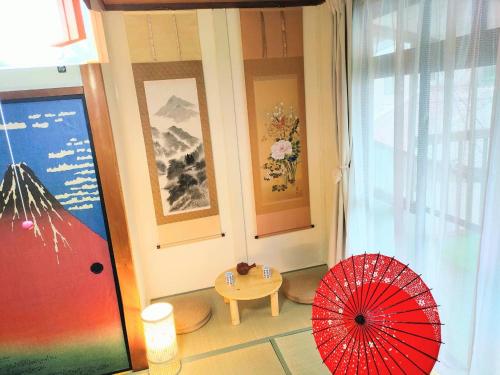 Pokój z czerwonym parasolem i stołem w obiekcie Masaki 1chome house w mieście Nagoja