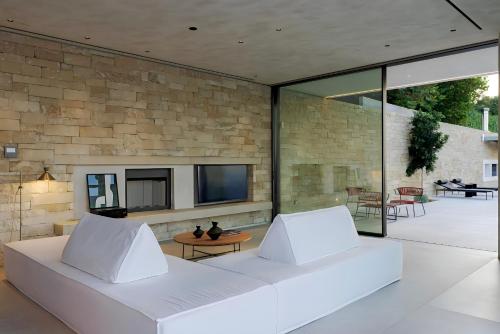 a living room with a white couch in front of a stone wall at Opsis villas, A waterfront & architectural retreat in Akrotiri