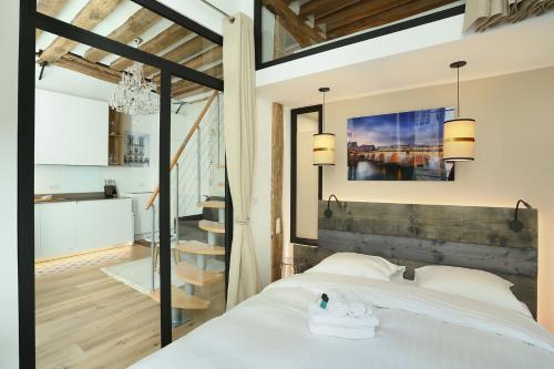een slaapkamer met een wit bed en een trap bij Résidence Le Marais by Studio prestige in Parijs