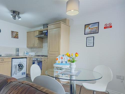 une cuisine avec une table et des chaises dans une pièce dans l'établissement Deluxe 2-bed apartment with free parking, netflix & fast WiFi, à Farnworth