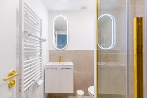 La salle de bains est pourvue d'un lavabo, de toilettes et de deux miroirs. dans l'établissement Lavie Maison Equipped Studio, à Bordeaux