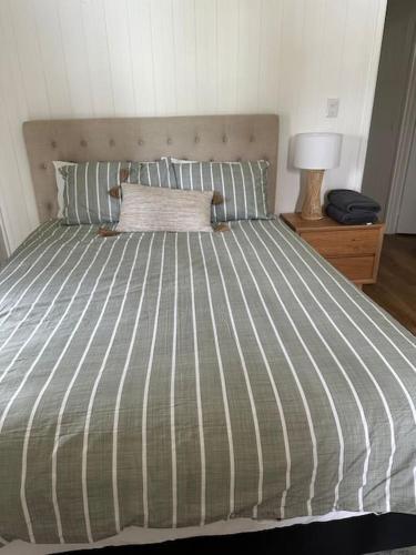 a bed with a green and white striped comforter at Rustic Retreat: The Lodge Lurg Sanctuary in Upper Lurg