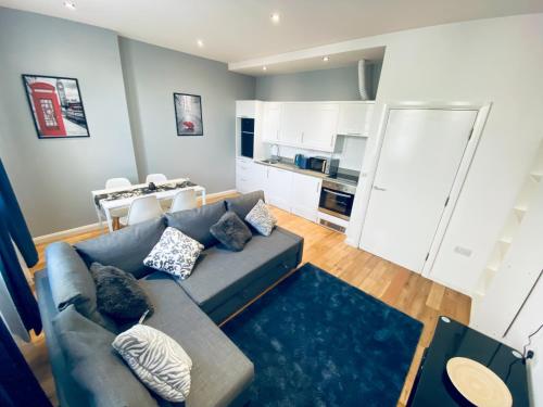 sala de estar con sofá azul y cocina en 2 Bed Flat - 2 Bath - 15 min Camden Town en Londres