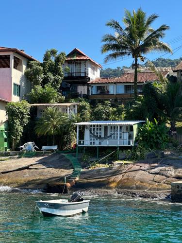 a boat in the water in front of a house at Cabana Do Mar in Angra dos Reis