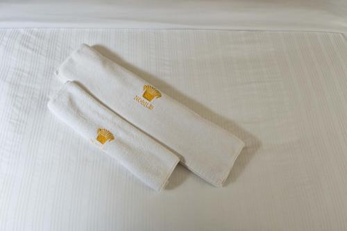 two white towels sitting on top of a bed at Nobilis Hotel and Apartments in Kigali