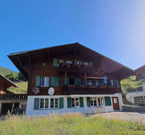 格林德尔瓦尔德Chalet Engi Apt. 3 for up to 8 People的一座大型木质建筑,前面设有椅子