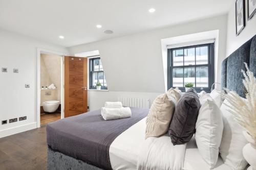 a white bedroom with a large bed with white pillows at 3BR Penthouse with Terrace - CityApartmentStay in London