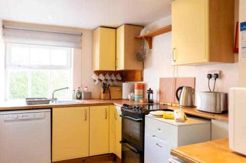 a kitchen with yellow cabinets and a sink at Cosy Cottage in the Norfolk Countryside in Whissonsett