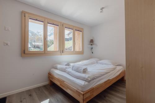 um quarto com uma cama com lençóis brancos e uma janela em Charmant studio rénové à Grimentz em Grimentz