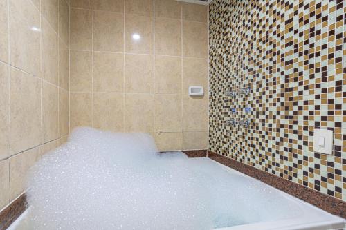 y baño con bañera llena de nieve. en Hotel Coqueiros 2 en Carapicuíba