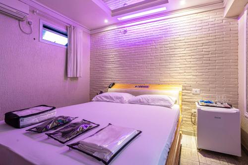 una camera con un letto bianco e un muro di mattoni di Hotel Coqueiros 2 a Carapicuíba