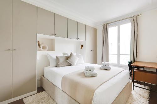 une chambre blanche avec un grand lit et un bureau dans l'établissement Pick A Flat's Apartment in Saint-Germain - Rue de Sèvres, à Paris