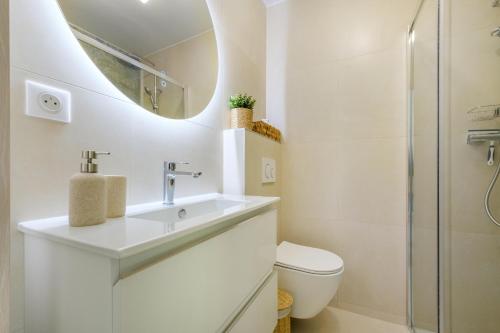 a white bathroom with a sink and a toilet at Appartement la Figurette vue mer in Théoule-sur-Mer