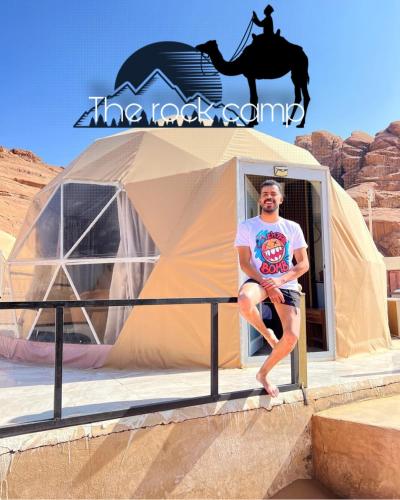 Un uomo seduto di fronte a una tenda con un cavallo di The Rock Camp a Wadi Rum