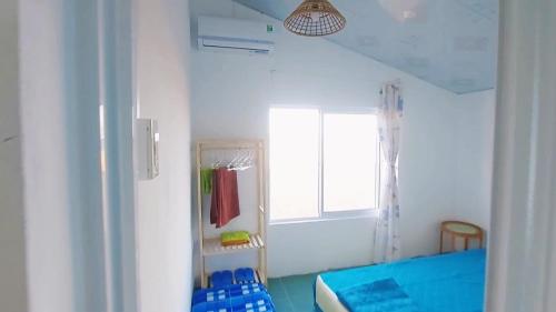 een slaapkamer met een blauw bed en een raam bij Homestay Bọt Biển in Phú Hiệp