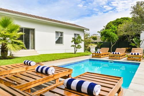 a swimming pool with benches and a house at Spray Villa Bloubergstrand with hot tub and close to the beach in Bloubergstrand