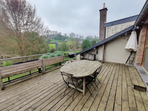 une terrasse en bois avec une table et des chaises. dans l'établissement Duplex 130 m2 avec terrasse à Sassor (Theux), à Theux