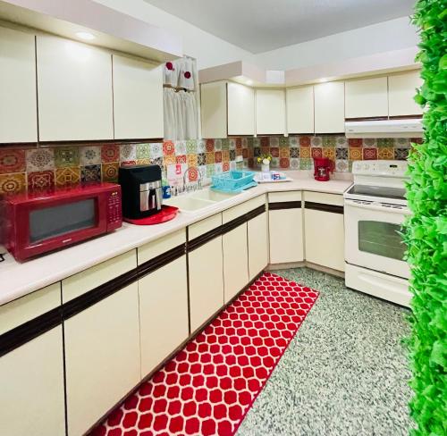 a kitchen with white cabinets and a red rug on the floor at Villa Altiery Puerto Rico in Caguas