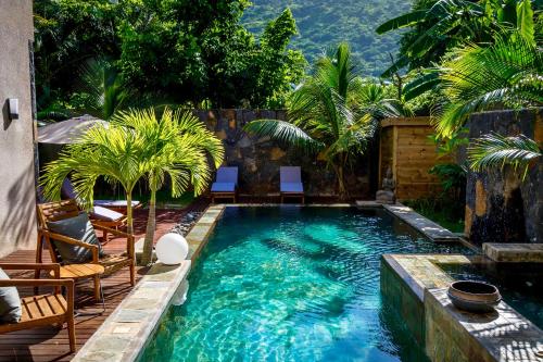 una piscina in un cortile con sedie e palme di Villa familiale 5ch, 5sdb proche plage et commerces a Rivière Noire