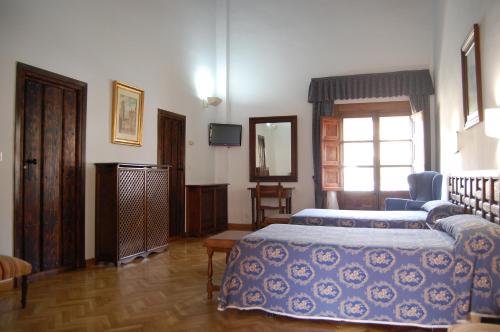 a hotel room with two beds and a window at Hospederia del Real Monasterio in Guadalupe