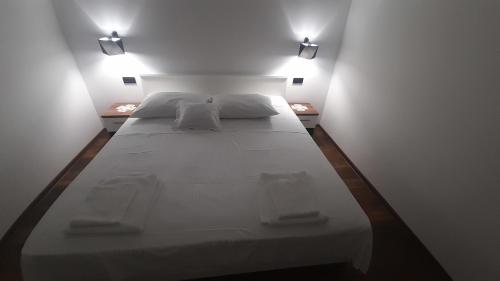 a large white bed in a room with two lights at Kampor Apartment 3 in Kampor