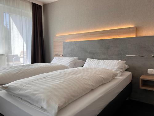 a bedroom with two white beds and a large window at Hotel Haus am Hochwald in Hahnenklee-Bockswiese