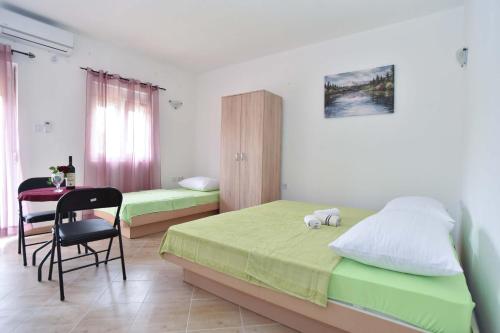 a bedroom with two beds and a table and a chair at Apartmani Mihovic - JAZ in Budva