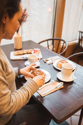 パリにあるラ メゾン モンパルナスのテーブルに座って食事を食べている女性