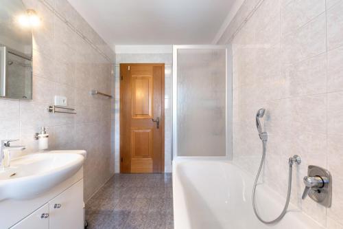 La salle de bains est pourvue d'une baignoire, d'un lavabo et d'une douche. dans l'établissement Mayr Apartments sechs, à Plaus