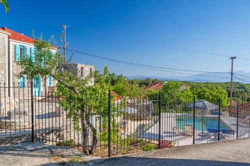 a fence in front of a house with a pool at Milia's House Ithaca in Anoyí