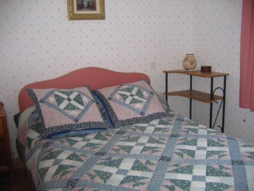 Schlafzimmer mit einem Bett mit Kissen und einem Tisch in der Unterkunft La chataîgneraie 