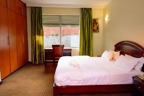 a bedroom with a white bed with a desk and a window at Nobilis Hotel and Apartments in Kigali