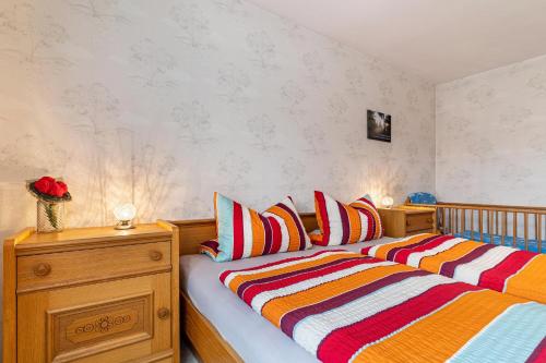 ヴォルフアッハにあるFerienwohnung Berghansenhofのベッドルーム1室(カラフルなストライプ枕付きのベッド1台付)