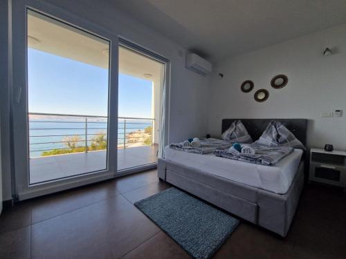 um quarto com uma cama e uma grande janela em Vera - Luxury Seafront Apartment em Klenovica