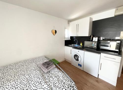 eine kleine Küche mit einem Bett und einer Mikrowelle in der Unterkunft Cosy Studio - London in London