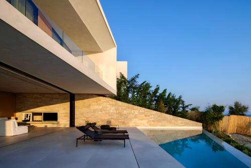 a house with a swimming pool next to a building at Opsis villas, A waterfront & architectural retreat in Akrotiri