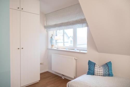 a small bedroom with a bed and a window at Spiekerhorst in Spiekeroog