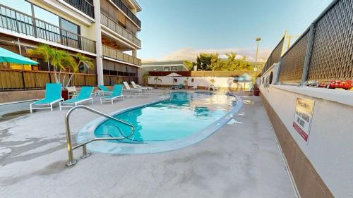 a swimming pool with blue chairs and a building at Kona Plaza 212 in Kailua-Kona