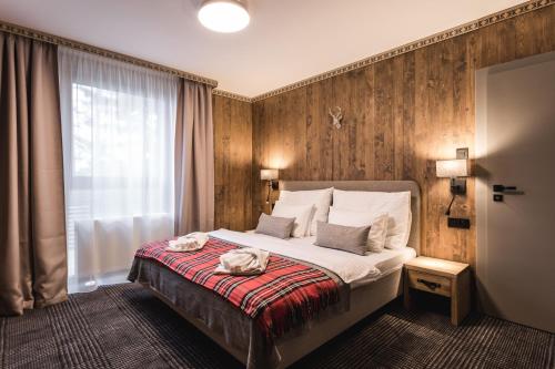 una camera d'albergo con un letto e due asciugamani di ARIETES MARMONT Resort a Tatranska Strba