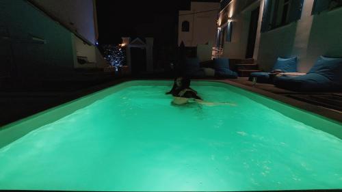 a woman sitting in a pool of green water at Mata's Apartments in Tinos Town