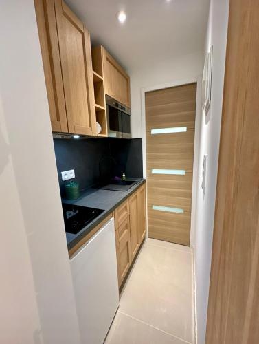 a kitchen with wooden cabinets and a white dishwasher at Villa Grand Baie in Agay - Saint Raphael