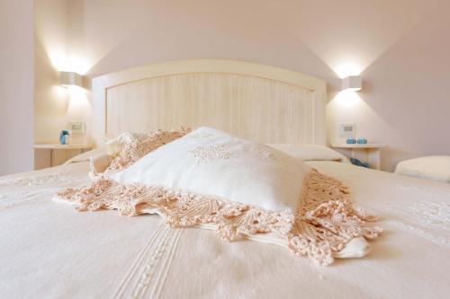 a white bed with a lace pillow on it at La rosa dei venti in Villasimius