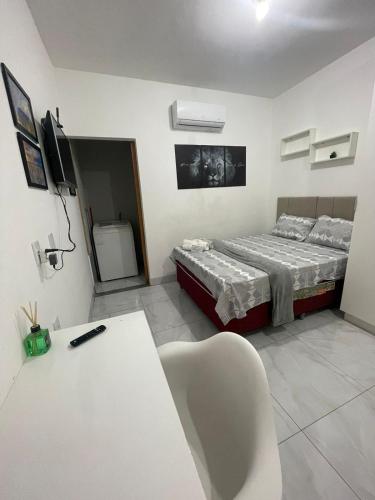 a room with a bed and a desk with a chair at Flat completo Aparecida de Goiânia in Aparecida de Goiania