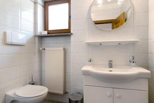 Un baño con lavabo, inodoro y espejo. en Mayr Apartments Drei, en Plaus