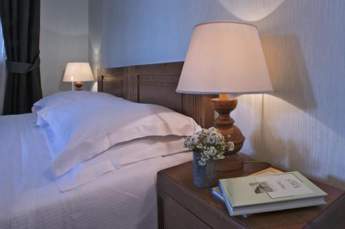 a bed with a table with a lamp and a book at Boutique Hotel Villa Blu Cortina D'Ampezzo in Cortina dʼAmpezzo